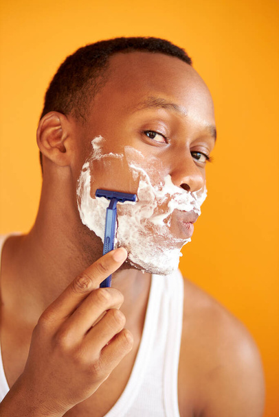 afro american on yellow background in foam shaving with a razor, portrait. - Photo, image