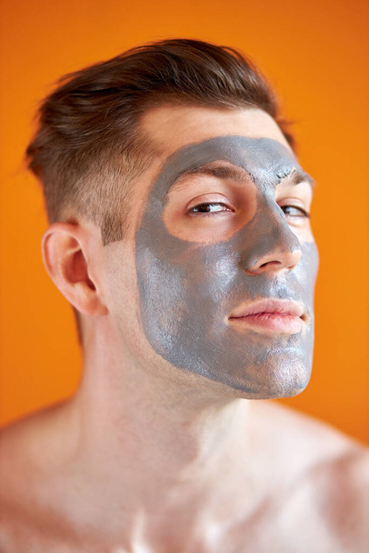 handsome young man receiving spa treatments, posing to camera on isolated yellow background - Foto, imagen