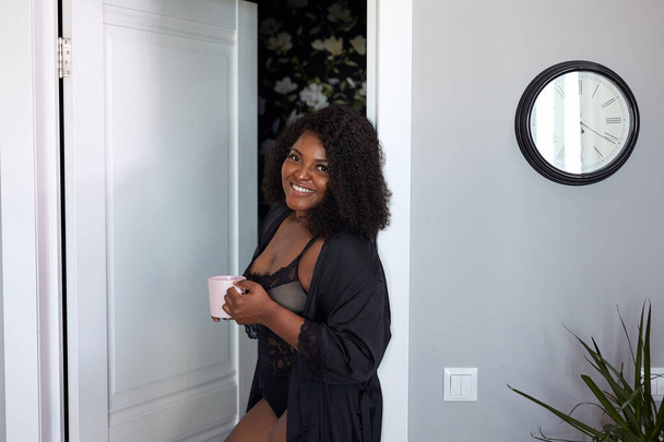 attractive plump black woman enter room holding cup of coffee - Foto, imagen