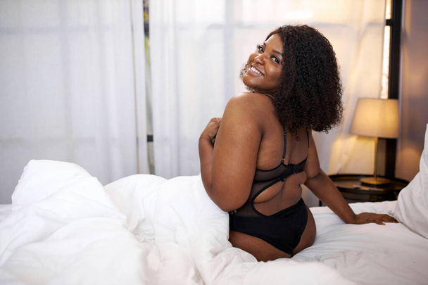 adorable afro woman smile sitting on bed - 写真・画像