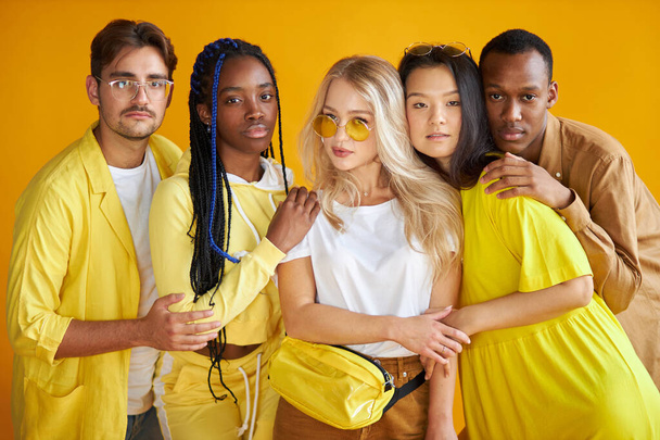 group of happy young men and women isolated on yellow background - Valokuva, kuva