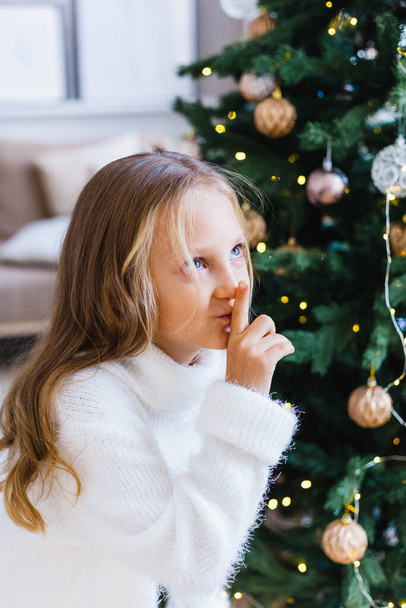 Girl with long hair in a white sweater around the Christmas tree, new year and Christmas tree, gifts - Foto, Bild