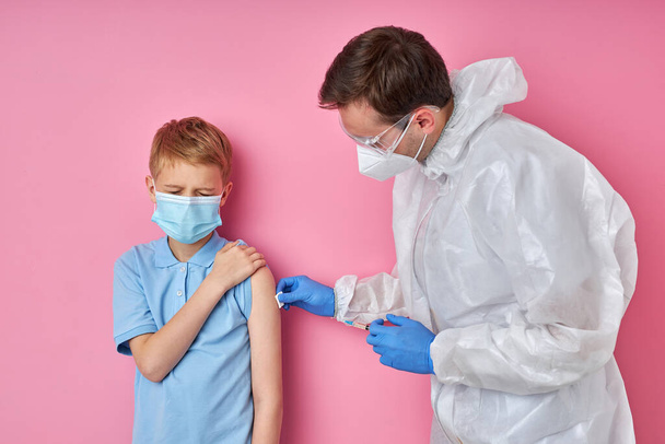 lääkäri haastaa ruiskun, joka antaa rokotetta pelästyneelle lapsipojalle sairaalassa - Valokuva, kuva