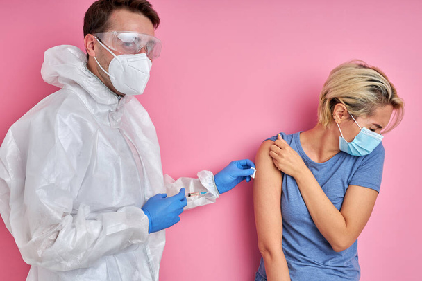 doctor giving vaccine shot to frightened caucasian woman - Foto, Imagen