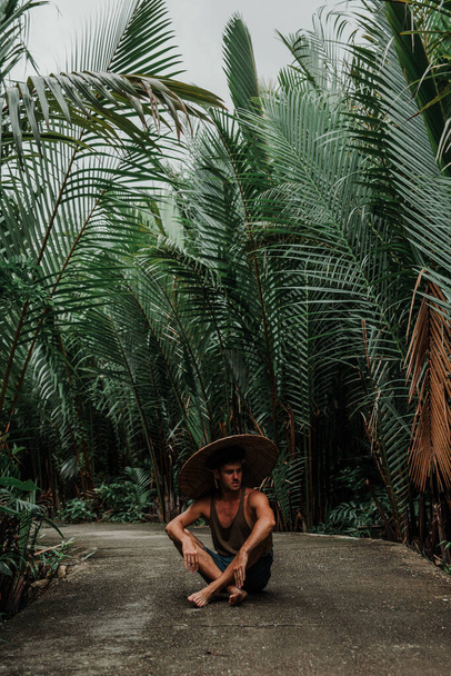 El tipo en el sendero en los trópicos, con un sombrero y una camiseta - Foto, Imagen