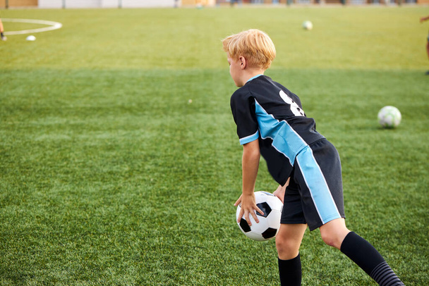 young kid boy training with ball alone in stadium - Zdjęcie, obraz