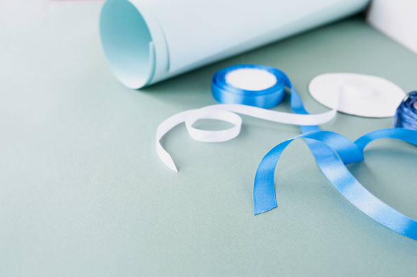 diy Christmas gifts packaging , bundle of white and blue satin ribbon and minimalistic rolls of paper for self-wrapping gifts. blue monochrome, selective focus - Foto, Bild