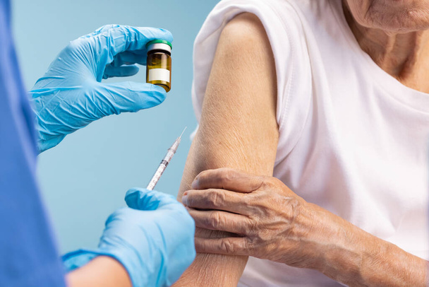 Closeup nurse doing vaccine injection to senior woman. - Photo, Image