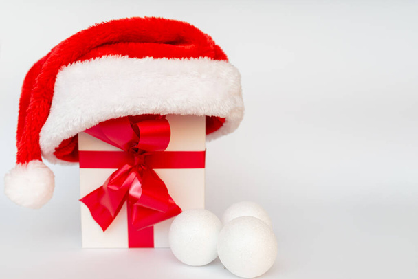 Presente de Natal com decoração de chapéu de santa bolas brancas de perto - Foto, Imagem
