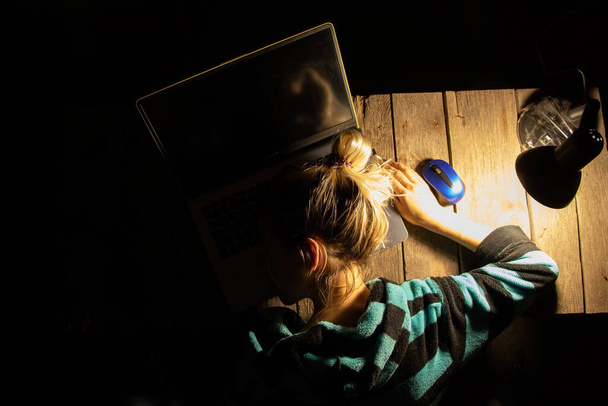 Mädchen schläft auf Laptop neben der Lampe am Tisch zu Hause, arbeitet zu Hause - Foto, Bild