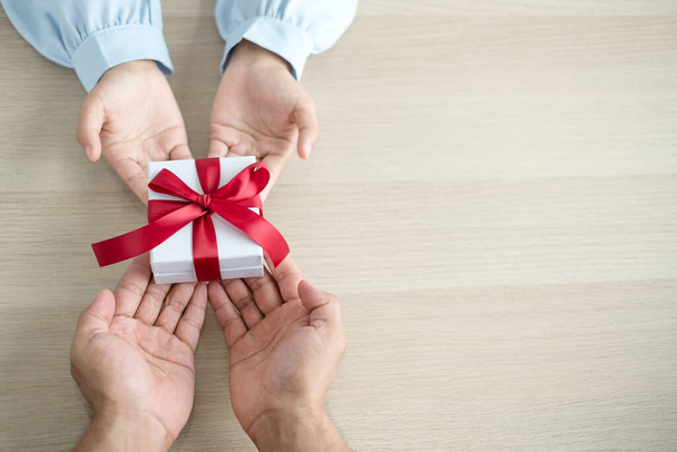 A hand holding a gift box Glad to be the giver of surprise with excitement, joy on the holidays, Christmas, birthdays, or Valentine's Day concept. - Photo, Image