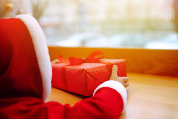 Little boy in santa costume open a christmas gift. Winter holiday, New Year. - Foto, Imagem