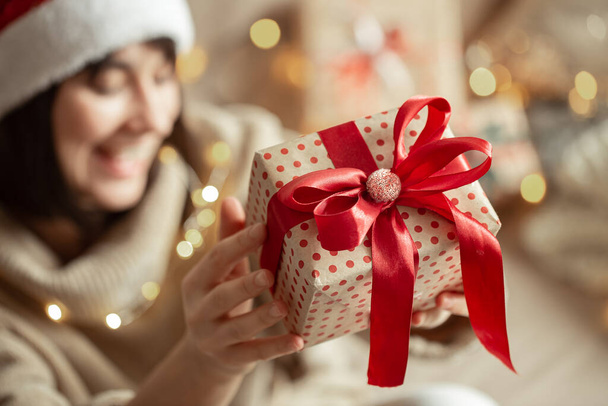 Christmas gift close up in female hands on a blurred background. Concept of gifting a present. - Fotografie, Obrázek