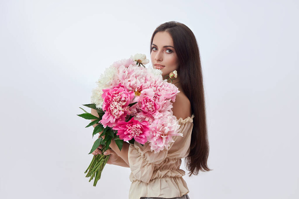 Beautiful woman with lots of pink flowers in her hands. Sexy woman with long hair - Photo, Image