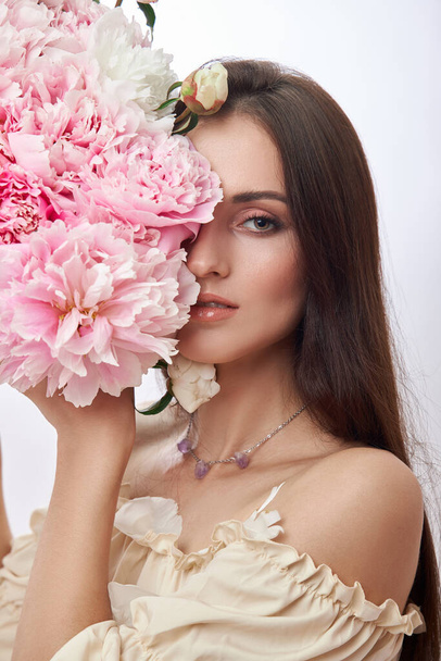 Beautiful woman with lots of pink flowers in her hands. Sexy woman with long hair - 写真・画像
