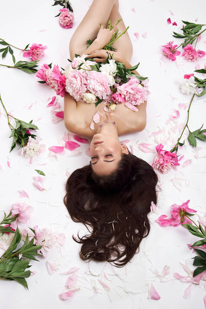 Beautiful woman with lots of pink flowers in her hands. Sexy woman with long hair - Φωτογραφία, εικόνα