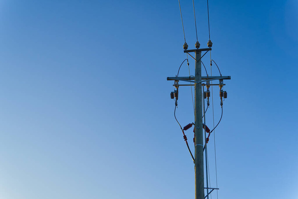 líneas de energía eléctrica cielo y conexiones en un poste de madera. Líneas eléctricas y cables con cielo azul. poste de electricidad de madera contra cielo azul. - Foto, imagen