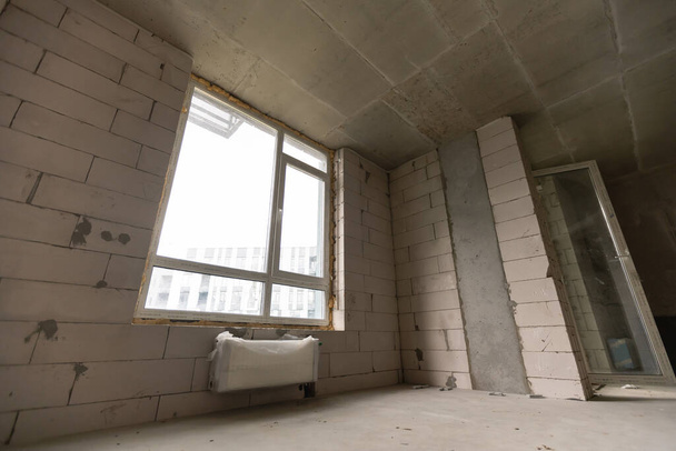 Nový nedokončený bytový pokoj s holými cihlovými zdmi bez výzdoby. - Fotografie, Obrázek