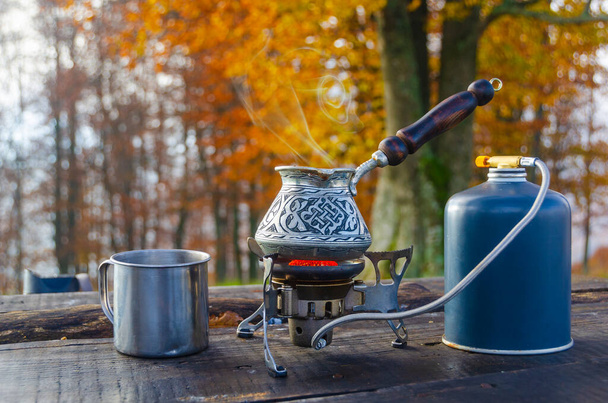 Hot coffee on a camping stove. Prepairing hot drink outdoors. Vacation and travel.  - Photo, Image