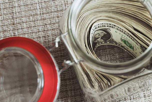 Keeping cash in a glass jar is a meager family budget - saving dollars from paycheck - 写真・画像