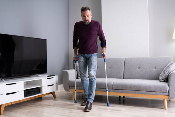 Elderly Man Using Crutches To Walk On Carpet - Фото, изображение