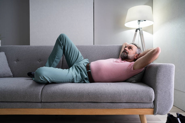 Senior Man Relaxing On Sofa In Living Room - Fotoğraf, Görsel