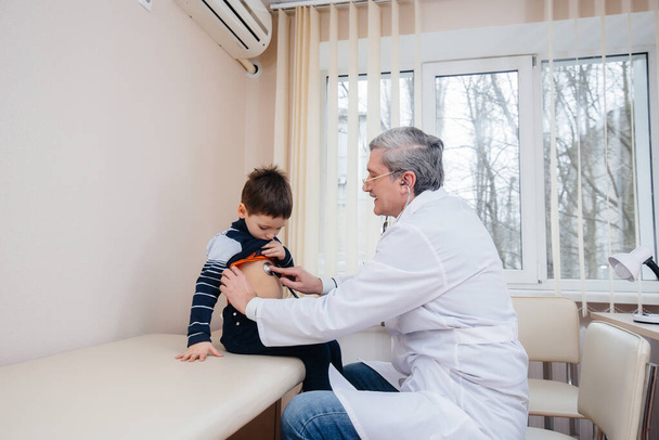 A young boy is listened to and treated by an experienced doctor in a modern clinic. A virus, and an epidemic - Fotografie, Obrázek