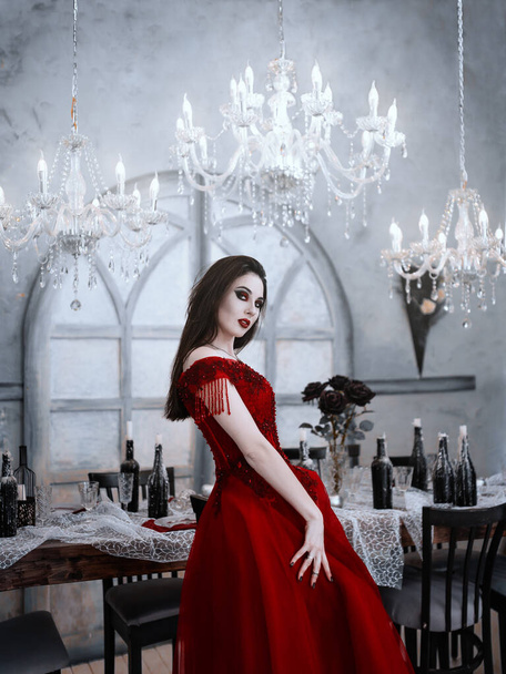 Bloodthirsty female vampire in red dress. Medieval interior - Valokuva, kuva