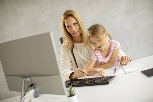 Lavorare madre con la sua graziosa figlia in ufficio - Foto, immagini
