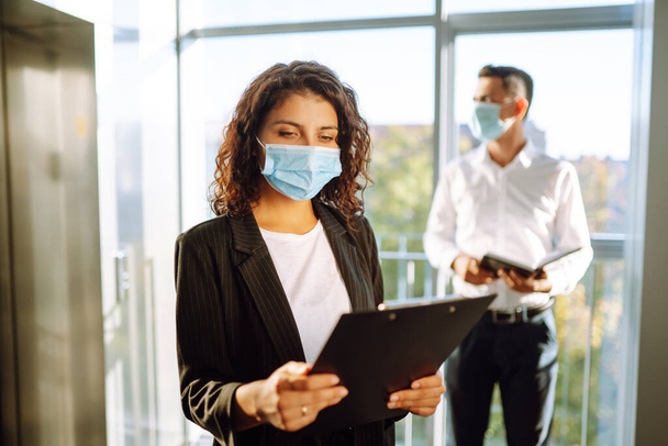 Young business woman wear face mask protect of coronavirus standing near elevator at modern office. Covid-19. - Fotoğraf, Görsel