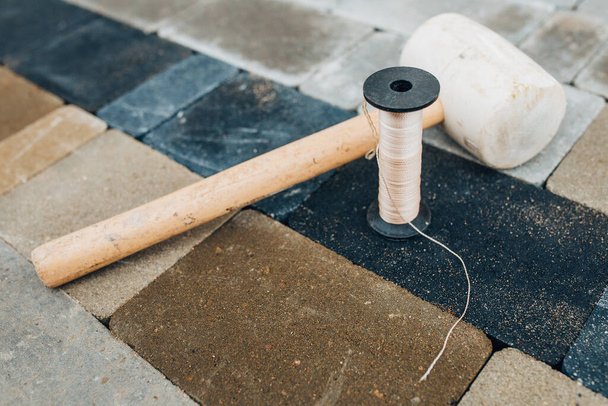 A straight line chopping cord and a rubber mallet with a wooden handle are a bricklayer tools for laying paving slabs - Valokuva, kuva