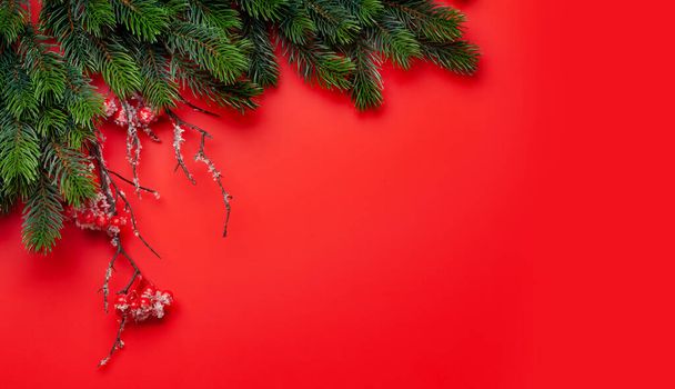 Χριστουγεννιάτικη ευχετήρια κάρτα με έλατο πάνω από κόκκινο φόντο. Top view επίπεδη θέσει με χώρο για τα Χριστούγεννα χαιρετισμούς σας - Φωτογραφία, εικόνα