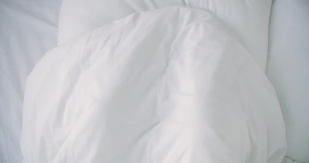 woman Peeking under duvet and smiling. Smiling cheerful woman peeking out from under the blanket in bed at home and kissing camera - Footage, Video