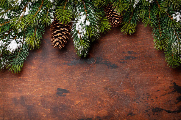 Tarjeta de felicitación navideña con abeto y conos de pino sobre fondo de madera y espacio de copia para sus saludos de Navidad. Vista superior plano laico - Foto, imagen