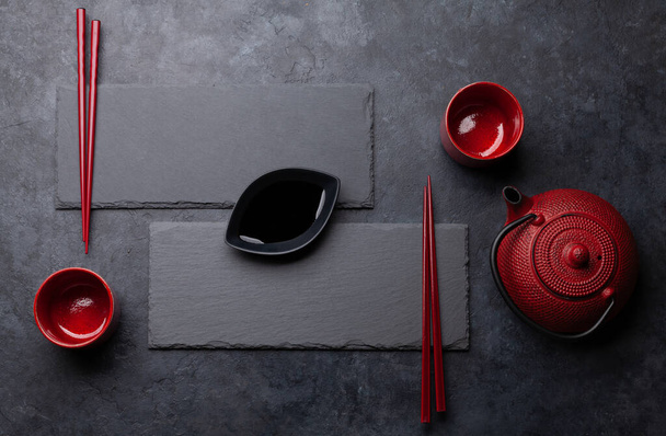 Kamienne talerze i pałeczki na sushi i maki. Japońskie menu w tle. Widok z góry płaski leżał z miejsca kopiowania - Zdjęcie, obraz