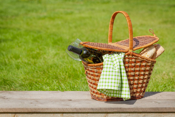 Piknikový koš s vínem a bagetou na slunné trávě. S mezerou pro kopírování - Fotografie, Obrázek