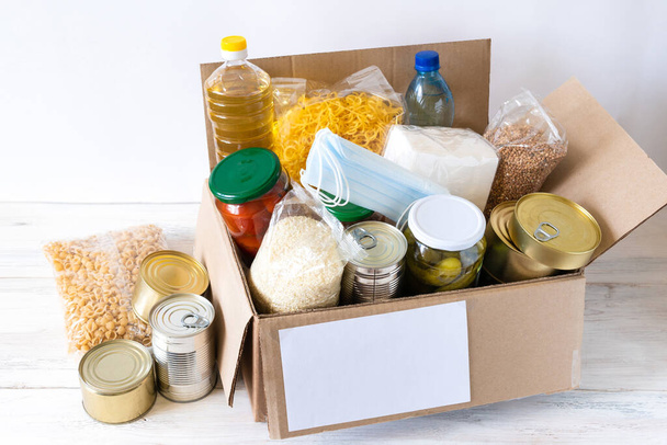 Donation box with various food. Open cardboard box with oil, canned food, cereals and pasta. - Photo, Image