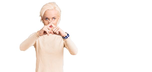 Молода блондинка в повсякденному одязі відмовляється перетинати пальці роблячи негативний знак
  - Фото, зображення