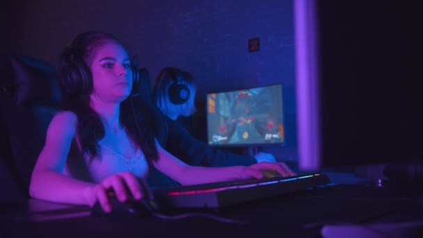 Две симпатичные девушки-геймеры играют в онлайн-шутер в неоновом игровом клубе - Кадры, видео