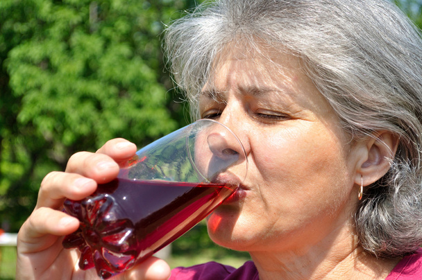 Γυναίκα πίνει διατηρημένα με απλή ψύξη χυμό κερασιού - Φωτογραφία, εικόνα