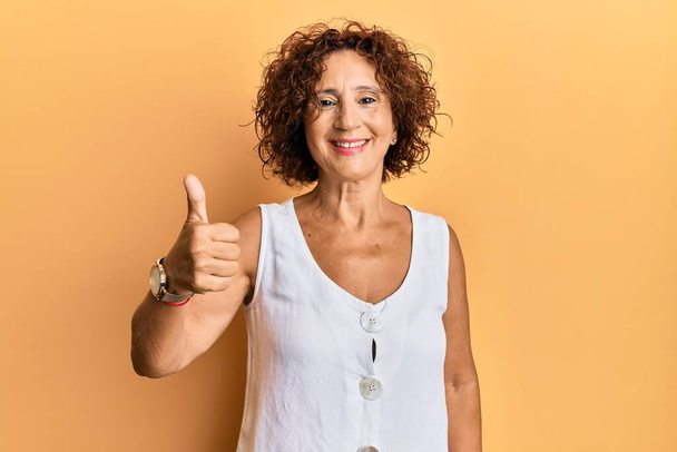 Beautiful middle age mature woman wearing casual clothes smiling happy and positive, thumb up doing excellent and approval sign  - Photo, Image