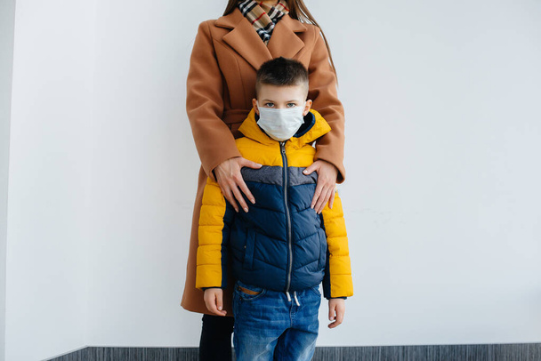 A mother with her child stands in a mask during the quarantine. Pandemic, coronavirus - Foto, Imagen