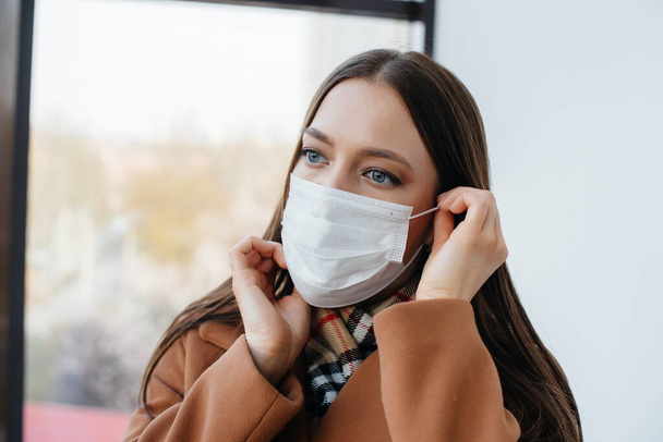 A young girl walks in a mask during the pandemic and coronovirus. Quarantine - Φωτογραφία, εικόνα