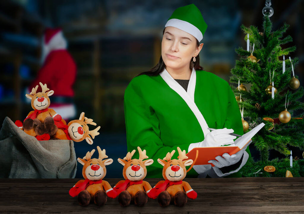 Olhe para a oficina mágica de Papai Noel como um elfo está verificando brinquedos - Foto, Imagem