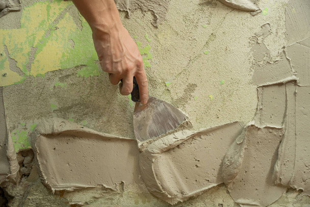Bir işçi duvarı spatulayla kaplıyor ve çimento karışımı solüsyonu uyguluyor. Tamirci alçıpanı alçıpan üzerine serer. Tamirci evi tamir ediyor. İşçi konutu restore eder. Uzman çatlakları kapatıyor. - Fotoğraf, Görsel