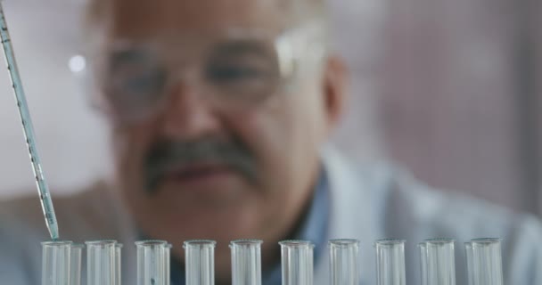 Wetenschapper druppel vloeistof in een reageerbuis en schudden in het laboratorium. Pipet druppelend een gekleurde chemische stof in een reageerbuis. Close-up van Science Man Werken - Video