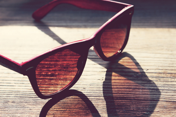 Óculos de sol vintage preto e vermelho em uma mesa de madeira closeup
 - Foto, Imagem