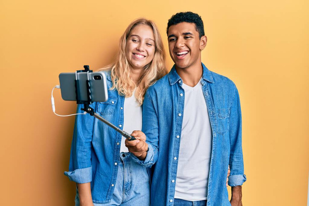 Mladý mezirasový pár se selfie foto s smartphonem s úsměvem a hlasitě se smát, protože legrační bláznivý vtip.  - Fotografie, Obrázek