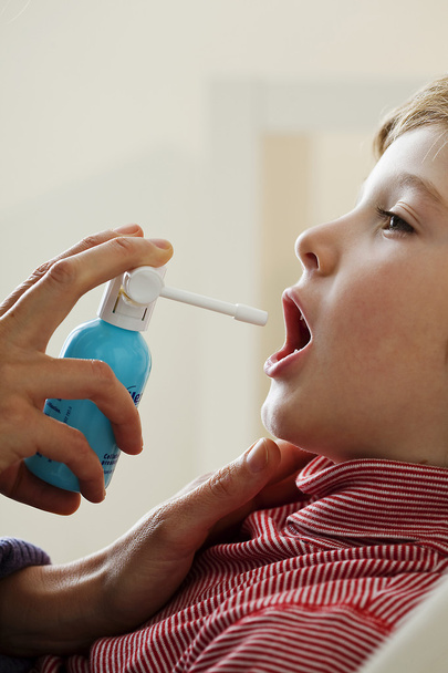 kind met behulp van spray in mond - Foto, afbeelding