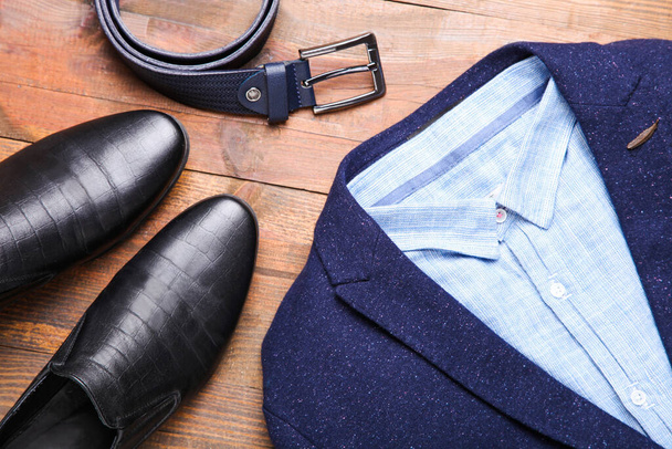 Traje clásico de hombre azul con zapatos de cuero negro y un cinturón sobre fondo marrón. Ropa de hombre. - Foto, imagen